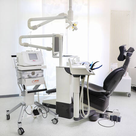 Moderne Zahnarztpraxis mit Behandlungsstuhl, Dental-Lasergerät und heller Einrichtung.